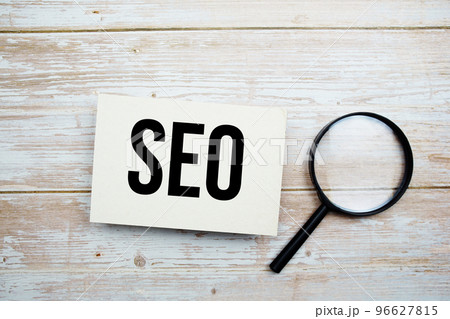 SEO text message and magnifying glass with space copy on wooden background SEO text message and magnifying glass with space copy on wooden background 96627815