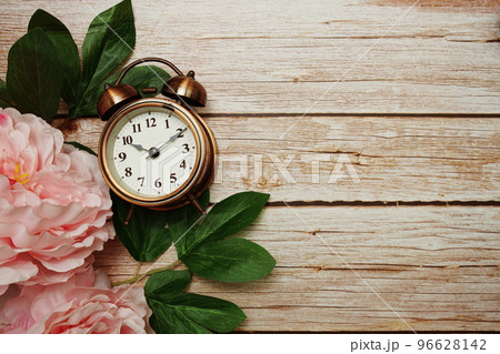 Alarm clock with pink peony flowers border frame on wooden background 96628142