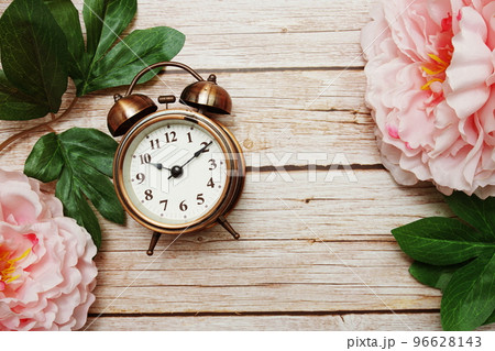 Alarm clock with pink peony flowers border frame on wooden background 96628143