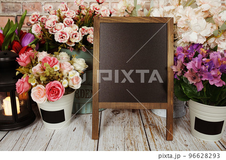 Easel blackboard empty mock up space for copy with flower decoration on wooden background 96628293