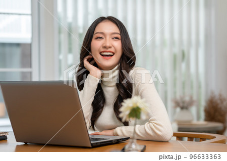 beautiful asian young woman wear casual sit on couch using computer laptop entertain with social media relax smile and laughing.Freelance woman working online sale marketing. Shopping online at home 96633363