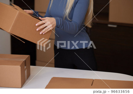 Caucasian girl taping boxes for moving in new apartment. Caucasian girl taping boxes for moving in new apartment. 96633656