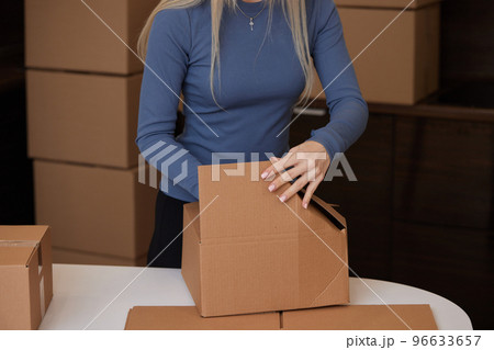 Caucasian girl taping boxes for moving in new apartment. 96633657