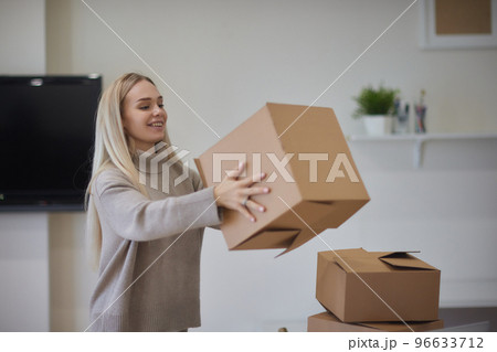 Caucasian girl taping boxes for moving in new apartment. Caucasian girl taping boxes for moving in new apartment. 96633712