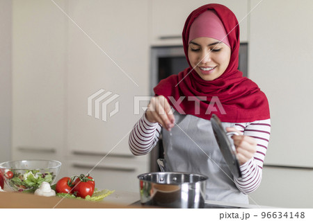Pretty middle eastern woman seasoning food, cooking at home 96634148