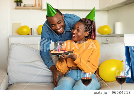 Husband's birthday. African american wife surprising husband with birthday cake, man enjoying b-day celebration at home 96634218