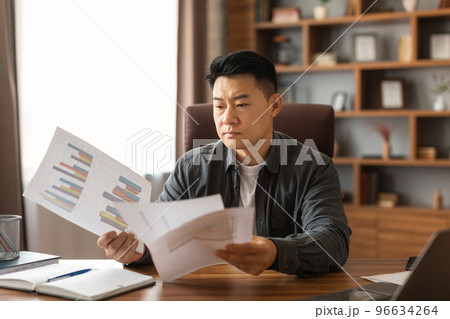 Busy serious concentrated middle aged asian man reads documents, think about project in home office interior 96634264