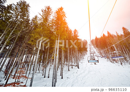 Ski lift at ski resort Bukovel in the mountains on a sunny winter day. Sun flare Ski lift at ski resort Bukovel in the mountains on a sunny winter day. Sun flare 96635110
