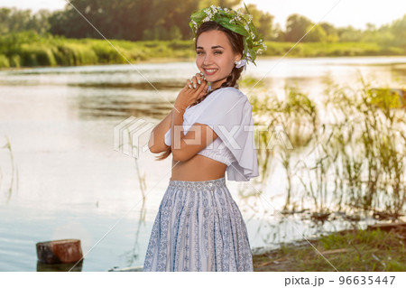 Young beautiful caucasian woman standing at the bank of river. Traditional countryside picture with girl at foreground and copy space. 96635447