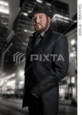 Film noir. Retro style fashion portrait of a detective. A man in a suit against a background of a night city 96635491
