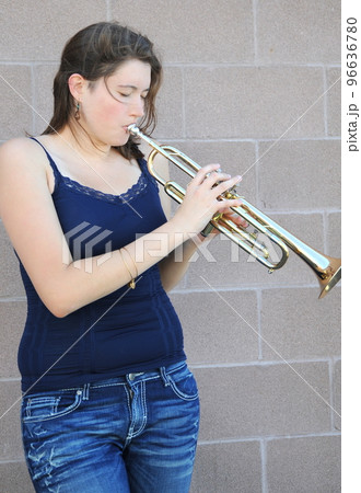 Female trumpet player blowing her horn outside. Female trumpet player blowing her horn outside. 96636780