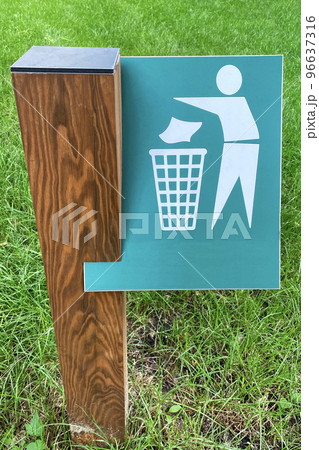 Sign of throw the trash in the trash can on background of green grass in park. Symbol on metallic plate. Sign of throw the trash in the trash can on background of green grass in park. Symbol on metallic plate. 96637316