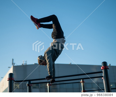 Young caucasian man doing parallel bars exercise outdoors.  96638084