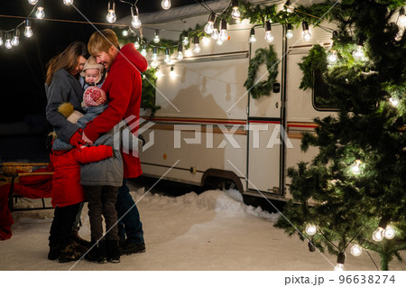 Happy caucasian family hugging outdoors. Christmas decorations. Parents and three sons travel in a camper.  96638274