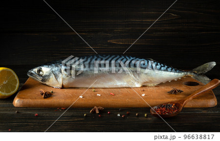 Mackerel fish on a kitchen table cutting board with ingredients and spices before cooking a fish food. Free space for advertising. 96638817