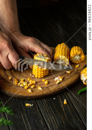 The chef cuts corn with a knife. Maize is an excellent dietary breakfast or lunch prepared by the cook hands 96638822