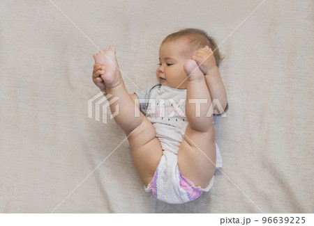 beautiful baby in a diaper lifted his legs to his head beautiful baby in a diaper lifted his legs to his head 96639225