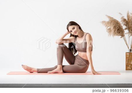 Beautiful yogi asian girl sitting on a fitness mat in a yoga room. Beautiful yogi asian girl sitting on a fitness mat in a yoga room. 96639306
