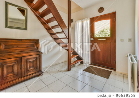 White hallway with wooden stairway leading to second floor of modern luxury apartment with minimalist interior design White hallway with wooden stairway leading to second floor of modern luxury apartment with minimalist interior design 96639558