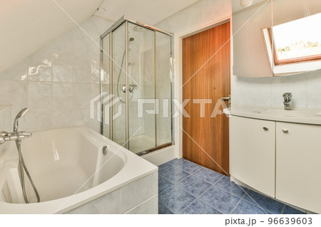 Sinks with mirrors and clean bathtub located near shower box with glass door in modern bathroom with white tiled walls 96639603