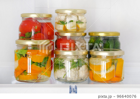 Variety glass jars homemade pickled vegetables stand in fridge. Fermented healthy natural vegetarian food concept. Variety glass jars homemade pickled vegetables stand in fridge. Fermented healthy natural vegetarian food concept. 96640076