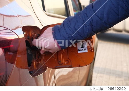 Man unscrews fuel filler cap in car. Fueling car with petrol pump at gas station. Petrol station. Diesel inscription. Close up. 96640290
