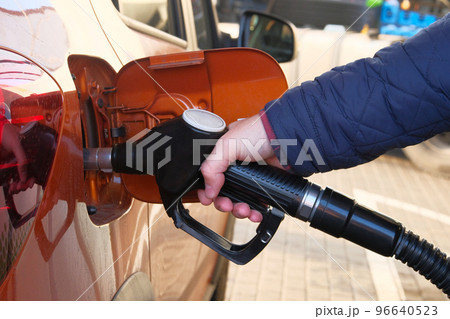 Man fills up his orange car with a gasoline at gas station. Gas station pump. To fill car with diesel fuel. 96640523