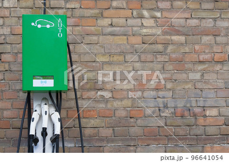 Electric cars charging concept. Electric vehicle charger station installed on vintage brick wall. Modern technology and old buildings. 96641054