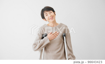 安堵の表情をする松葉杖をついたミドル女性　医療保険イメージ 96643423