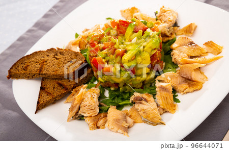 Salad guacamole with fresh tomatoes and arugula served with trout fillet Salad guacamole with fresh tomatoes and arugula served with trout fillet 96644071