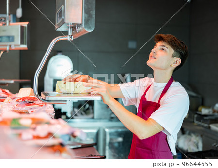 Young salesman weighing cheese on a scale in grocery store 96644655