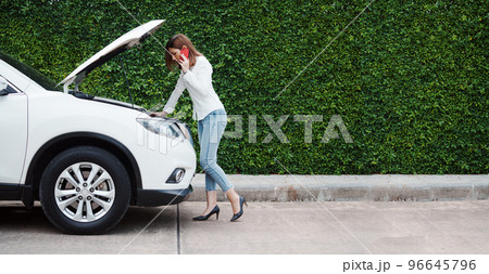 Young woman in a car broke down on the road trying to fix the problem and called a car repair shop or someone close to help. Young woman in a car broke down on the road trying to fix the problem and called a car repair shop or someone close to help. 96645796