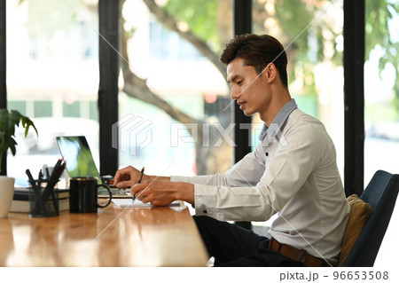 Millennial businessman managing company investment strategy and using laptop in bright modern office 96653508
