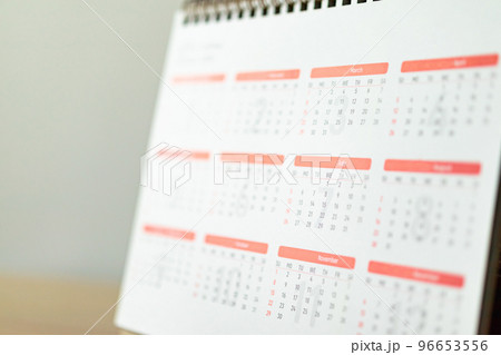 Calendar page close up on wood table with white wall background business planning appointment meeting concept Calendar page close up on wood table with white wall background business planning appointment meeting concept 96653556
