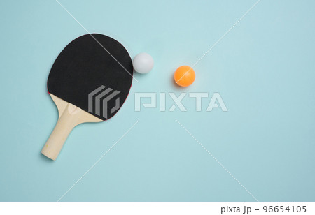 Wooden tennis racket for ping pong and a plastic ball on a blue background Wooden tennis racket for ping pong and a plastic ball on a blue background 96654105