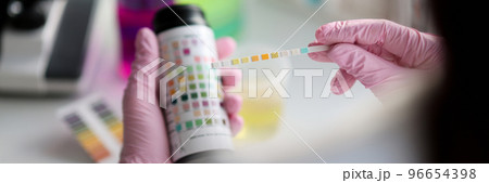 Clever scientist hold litmus test paper for soil analysis, papers show acidity Clever scientist hold litmus test paper for soil analysis, papers show acidity 96654398