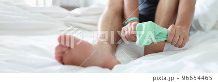 Man try to pull sock on foot, dress up to go out, sit on bed for comfort 96654465