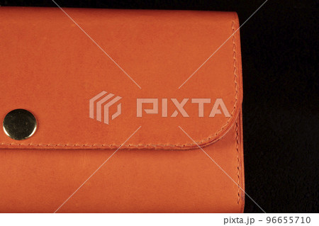 Part of an orange leather wallet on a dark background. Part of an orange leather wallet on a dark background. 96655710