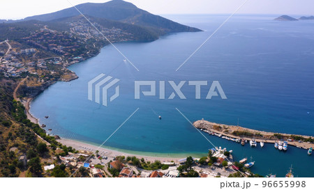 Aerial drone view of coastal town with green mountains. Turquoise sea bay with boats anchored at harbor. Antalya province, Turkey. 96655998