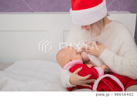 Caucasian woman breastfeeding her son in santa claus costume. 96656402