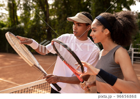 Male coach showing the girl how to hold the tennis racket Male coach showing the girl how to hold the tennis racket 96656868