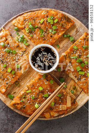 Korean Pancakes Kimchijeon is basically made with kimchi and a little scallions closeup on the wooden board. Vertical top view Korean Pancakes Kimchijeon is basically made with kimchi and a little scallions closeup on the wooden board. Vertical top view 96658152