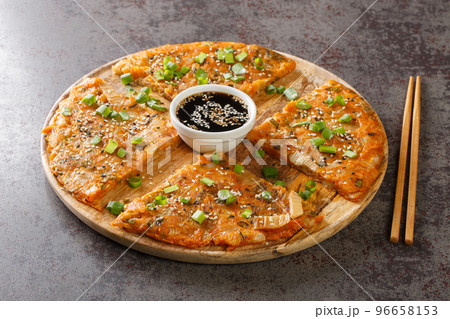 Kimchijeon is a Korean savory crispy pancake made of kimchi with flour and onion closeup on the wooden board. Horizontal Kimchijeon is a Korean savory crispy pancake made of kimchi with flour and onion closeup on the wooden board. Horizontal 96658153