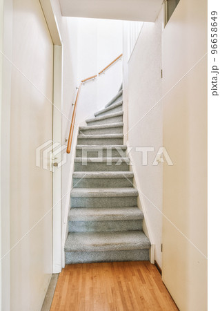 White hallway with wooden stairway leading to second floor of modern luxury apartment with minimalist interior design White hallway with wooden stairway leading to second floor of modern luxury apartment with minimalist interior design 96658649
