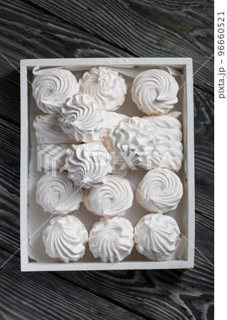 Homemade zephyr. White tray with marshmallows. Stands on black pine boards. 96660521