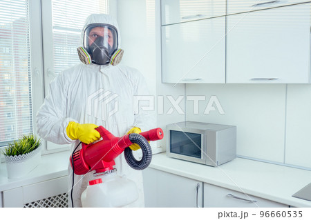pest control worker standing with sprayer in kitchen 96660535