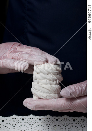 The woman will connect the halves of the marshmallow. Homemade zephyr. White tray with marshmallows. The woman will connect the halves of the marshmallow. Homemade zephyr. White tray with marshmallows. 96660715