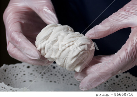 The woman will connect the halves of the marshmallow. Homemade zephyr. White tray with marshmallows. The woman will connect the halves of the marshmallow. Homemade zephyr. White tray with marshmallows. 96660716