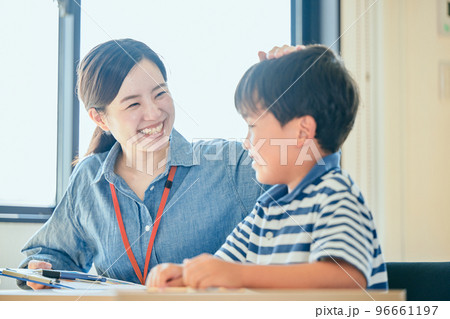 勉強する生徒を褒める若い塾講師 勉強する生徒を褒める若い塾講師 96661197