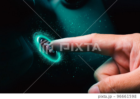 The driver palm as it presses the electric car engine start stop button with blue light illuminated The driver palm as it presses the electric car engine start stop button with blue light illuminated 96661598